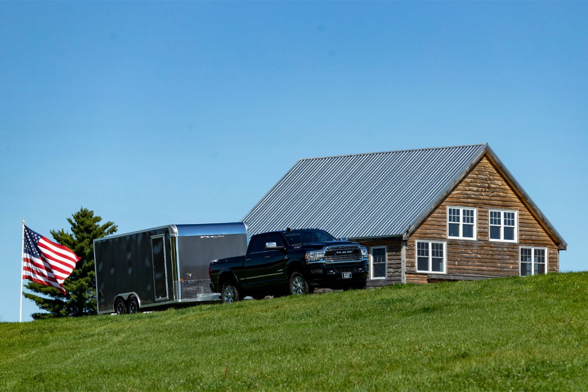 Black Truck Hauling Gray Enclosed Car Hauler Trailer Past House